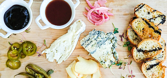 cheese, bread, and pickles on a wooden board