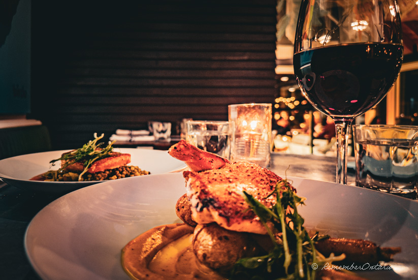 a plate of chicken sitting on a table next to a glass of wine