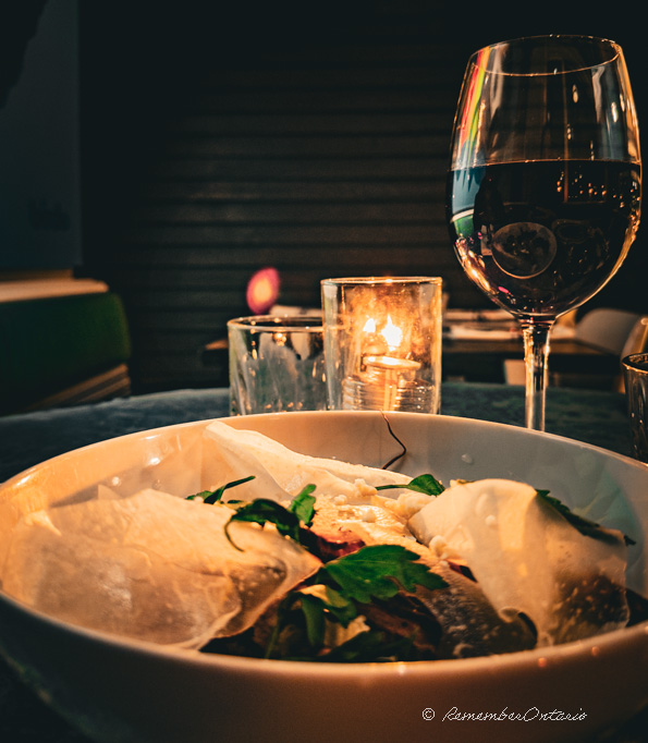 a bowl of root salad and a glass of wine on a table