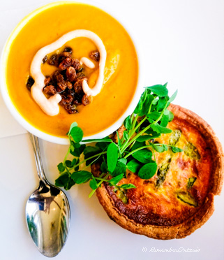 a bowl of soup and a quiche on a white plate