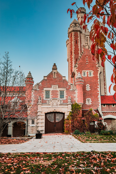 The entrance of the brick stable of Casa Loma with 2 turret and a high tower on its side.