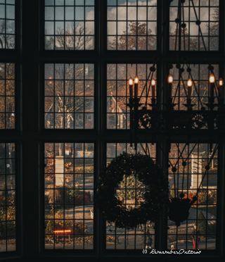 View through the staircase window that is decorated with wreaths.