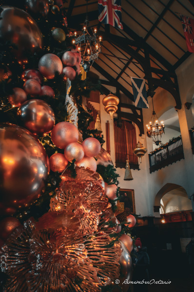 A Christmas tree decorated with large baubles stands inside the hall of Casa Loma.