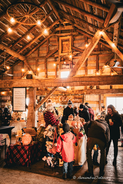 Kids and adults were shopping under a warm decorating light in side a wooden barn.